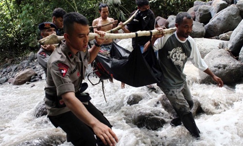 Cảnh s&aacute;t Indonesia v&agrave; d&acirc;n l&agrave;ng di chuyển thi thể của một nạn nh&acirc;n bị nước cuốn tr&ocirc;i. Ảnh: AFP
