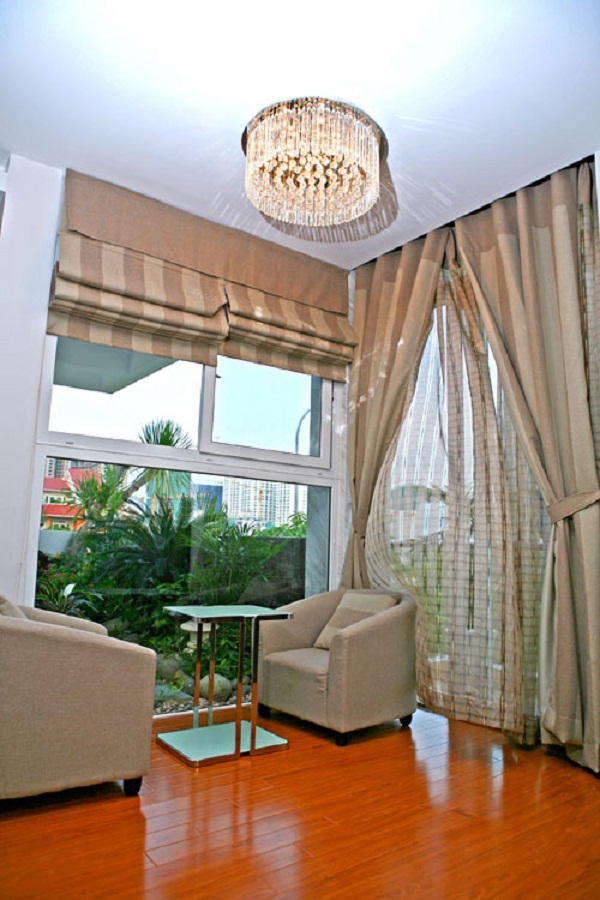 Một góc phòng ngủ với ghế sofa vuông dùng để cà phê sáng, nơi có thể nhìn ra ngoài khoảng lan can đầy hoa lá