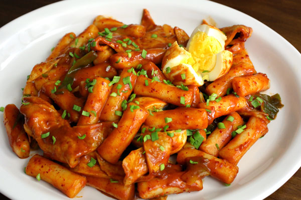Tokbokki hay còn gọi là bánh gạo cay. Đây là món ăn truyền thống rất được người dân Hàn Quốc ưa chuộng. Tokbokki được làm từ gạo, cắt thành từng khúc vừa ăn, sau đó nấu với bột ớt để cho ra màu sắc vô cùng mời gọi. Bạn có thể dùng tokbokki để ăn với lẩu, ngon tuyệt cú mèo! Tokbokki hiện nay được biến tấu thành rất nhiều món ăn đa dạng như tokbokki với mì tương đen, tokbokki xào với bột ớt và phủ một lớp phô mai phía trên…Trời mưa mà được ăn một dĩa tokbokki nóng hổi, vừa ăn vừa hít hà vị cay thì còn gì bằng.