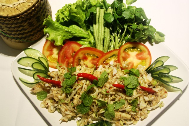 Trong tiếng Lào, món Laap (hay còn gọi là lạp) mang nghĩa may mắn, tượng trưng cho lời cầu chúc bình an. Nguyên liệu làm món ăn này có thể dùng thịt bò, thịt lợn, thịt gà… trộn với gan băm nhỏ và gia vị như nước cốt chanh, ớt, riềng. Sau khi trộn đều, món lạp sẽ ăn kèm rau sống như diếp cá, xà lách, đậu đũa… tất cả cùng hòa quyện tạo nên mùi thơm cực kỳ hấp dẫn. Vị chua của nước cốt chanh, vị cay của ớt, vị thơm của gia vị… đưa đến cho du khách một cảm nhận khó quên.
