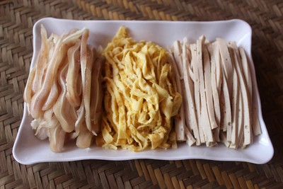 Trong khi chờ tai v&agrave; trứng nguội, th&aacute;i gi&ograve; theo sợi d&agrave;i v&agrave; nhỏ cho dễ cuống. Sau đ&oacute;, th&aacute;i sợi trứng v&agrave; tai lợn c&oacute; độ d&agrave;y, chiều d&agrave;i như gi&ograve; lụa.