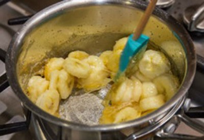 L&uacute;c n&agrave;y, thả c&aacute;c l&aacute;t chuối đ&atilde; cắt v&agrave;o, trộn đều chuối với caramel.