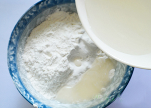 Trộn bột nếp với nước ấm: đổ từ từ từng ch&uacute;t nước v&agrave;o một để nh&agrave;o sao cho tất cả bột li&ecirc;n kết với nhau l&agrave; được.