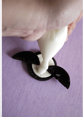 Đặt hai nửa kẹo socola l&ecirc;n phần b&aacute;nh kem của b&aacute;nh oreo. Cho kem phomat tươi v&agrave;o đui nhỏ, phủ k&iacute;n l&ecirc;n chiếc b&aacute;nh.