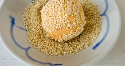 Lăn b&aacute;nh qua một lớp vừng rồi lại d&ugrave;ng tay v&ecirc; tr&ograve;n b&aacute;nh một lần nữa để cho vừng in v&agrave;o vỏ b&aacute;nh tr&aacute;nh việc bị rơi rụng khi r&aacute;n.