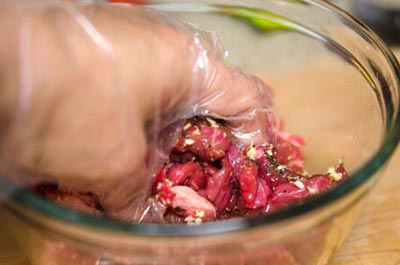 Tay đeo găng nilon sạch, trộn đều hỗn hợp thịt b&ograve; với c&aacute;c gia vị, ướp khoảng từ 15 đến 30 ph&uacute;t.