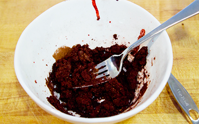 Cho bột cacao v&agrave;o t&ocirc;, sau đ&oacute; th&ecirc;m phẩm m&agrave;u v&agrave; vanilla v&agrave;o rồi khuấy đều.