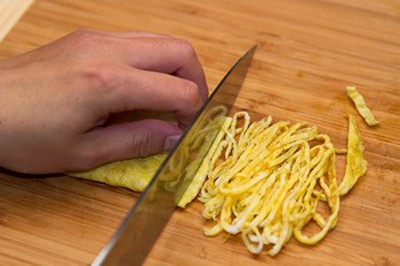Sau khi trứng nguội th&igrave; lấy ra rồi cuộn lại th&aacute;i sợi mỏng.
