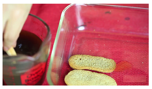 Nh&uacute;ng từng chiếc ladyfinger trong hỗn hợp nước cafe v&agrave; rượu Rum. Sau đ&oacute; xếp ladyfinger th&agrave;nh h&agrave;ng ngay ngắn v&agrave;o dưới đ&aacute;y khu&ocirc;n đ&atilde; chuẩn bị.