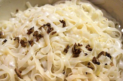 Sợi b&aacute;nh phở chần sơ qua nước s&ocirc;i cho mềm, xả lại nước lạnh, đổ b&aacute;nh phở ra rổ rưới một &iacute;t tỏi phi v&agrave; một &iacute;t dầu ăn l&ecirc;n bề mặt b&aacute;nh phở để chống d&iacute;nh.