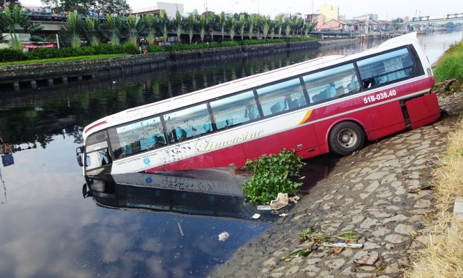 Xe kh&aacute;ch h&uacute;c bay dải ph&acirc;n c&aacute;ch, lao xuống k&ecirc;nh. Ảnh: Tuổi trẻ