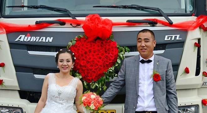C&ocirc; d&acirc;u v&agrave; ch&uacute; rể hạnh ph&uacute;c b&ecirc;n chiếc xe tải đầy hoa tươi trong đ&aacute;m cưới