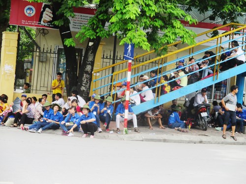 Tại điểm thi trường Đại học Kinh tế Quốc dân, phụ huynh ngồi la liệt trên cầu và dưới gầm cầu dành cho người đi bộ sang đường.