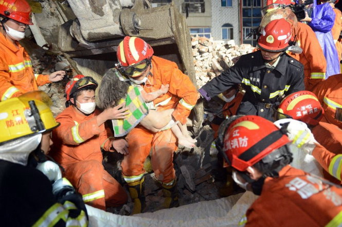  Cháu bé s&ocirc;́ng sót th&acirc;̀n kỳ sau vụ s&acirc;̣p nhà kinh hoàng. Ảnh: AFP 