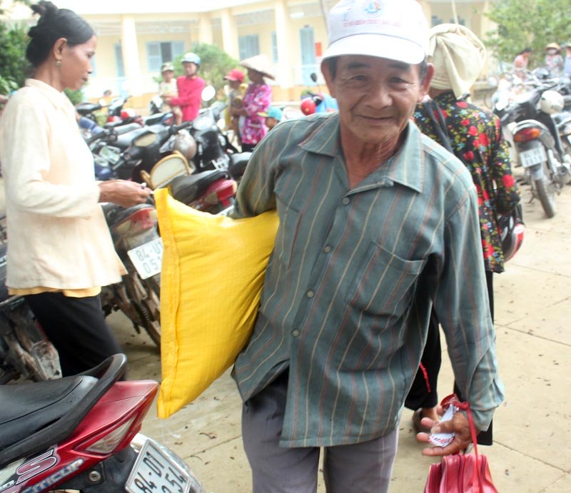  Người ngh&egrave;o đến đ&acirc;y được tặng gạo v&agrave; tiền mặt. Ảnh: Vietnamnet