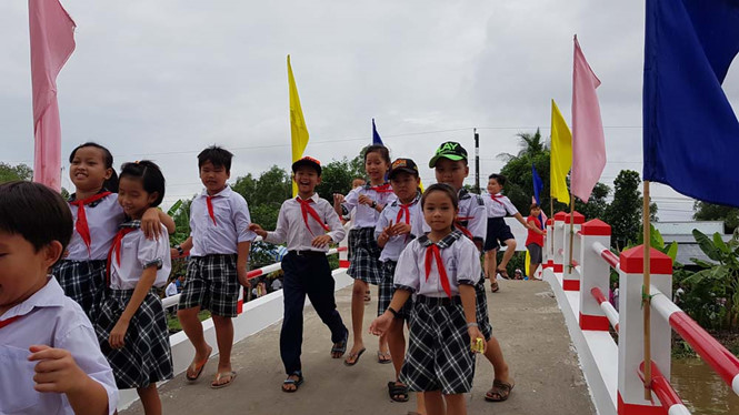 Nhiều em học sinh tiểu học hớn hở, vui hơn khi c&oacute; cầu mới do hoa hậu Kim Nguyễn t&agrave;i trợ. Ảnh: Thanh Ni&ecirc;n 