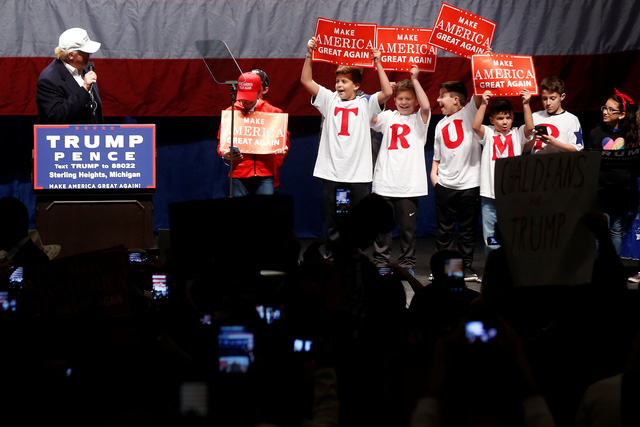 &Ocirc;ng Trump xuất hiện tr&ecirc;n s&acirc;n khấu tại cuộc vận động tranh cử ở Detroit, bang Michigan h&ocirc;m 6/11. Đứng kế b&ecirc;n &ocirc;ng l&agrave; c&aacute;c học sinh mang theo khẩu hiệu tranh cử &ldquo;L&agrave;m cho nước Mỹ vĩ đại trở lại&rdquo; của ứng vi&ecirc;n đảng Cộng h&ograve;a.