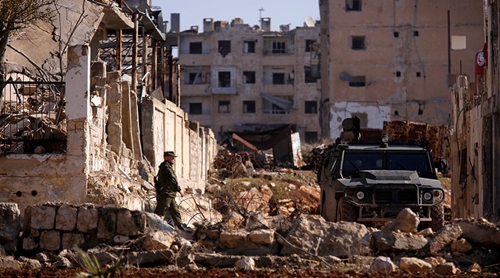 Chiến sự Syria: Một binh sĩ Nga h&ocirc;m 4/12 bước tới xe qu&acirc;n sự tại khu vực d&acirc;n cư Hanono do ch&iacute;nh phủ kiểm so&aacute;t tại Aleppo. Ảnh: Reuters 