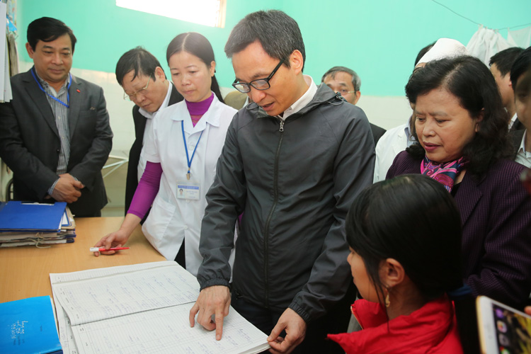  Ph&oacute; Thủ tướng xem một sổ ghi ch&eacute;p c&aacute;c trường hợp đến kh&aacute;m tại trạm y tế x&atilde; Minh Đức. Ảnh: VGP
