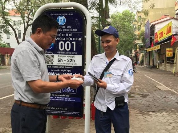  Kh&aacute;ch h&agrave;ng nhận h&oacute;a đơn từ nh&acirc;n vi&ecirc;n tr&ocirc;ng giữ phương tiện tại điểm đỗ sử dụng c&ocirc;ng nghệ iParking 001 tr&ecirc;n phố L&yacute; Thường Kiệt. Ảnh: Kinh tế & Đ&ocirc; thị
