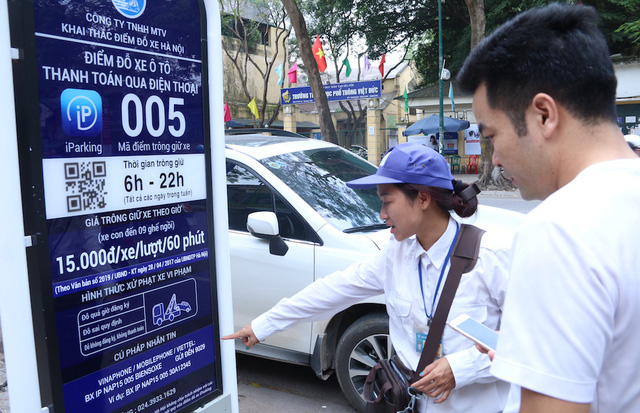 Nh&acirc;n vi&ecirc;n tr&ocirc;ng xe hướng dẫn người d&acirc;n sử dụng dịch vụ thanh to&aacute;n ph&iacute; gửi xe qua điện thoại. Ảnh: D&acirc;n tr&iacute;