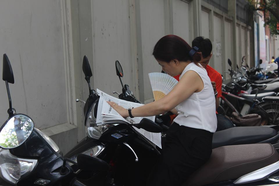  Một số phụ huynh ngồi đọc b&aacute;o chờ con hết giờ thi. Ảnh: &Aacute;nh Ng&acirc;n