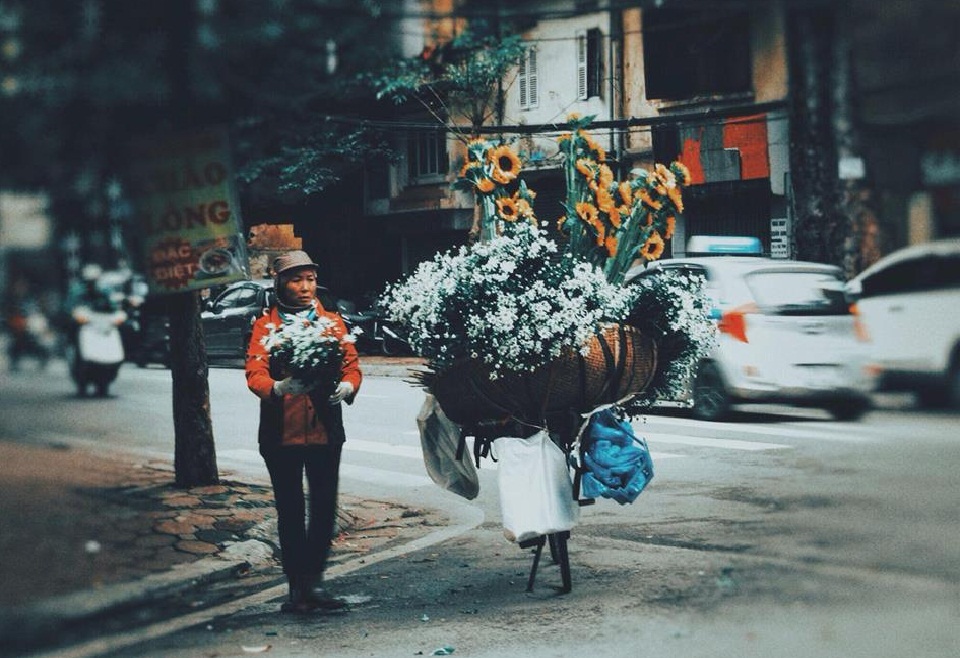 Người phụ nữ bán hoa dạo vẫn dậy từ sớm đi lấy hàng rồi đưa hoa tươi đi bán dọc phố trong mưa. Ảnh Sưu tầm