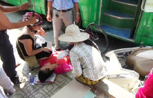 Người phụ nữ bị kẹt dưới b&aacute;nh xe bu&yacute;t được mọi người k&eacute;o ra ngo&agrave;i chờ chuyển đi cấp cứu