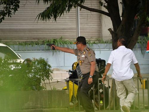 Một cảnh sát Indonesia chĩa súng nhắm vào nghi phạm trong quán cà phê Starbucks. Ảnh: AFP