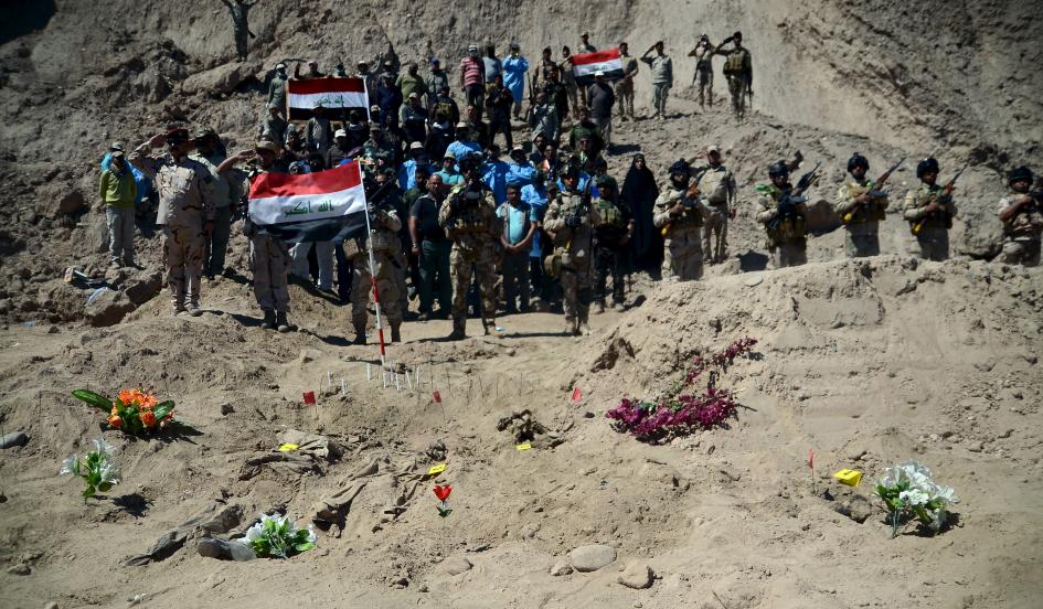 Binh sĩ Iraq thực hiện nghi thức ch&agrave;o b&ecirc;n cạnh ng&ocirc;i mộ tập thể những binh l&iacute;nh Shi'ite của khủng bố IS ở trại Speicher 