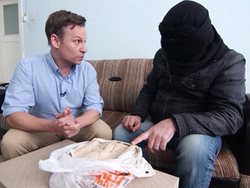 Abu Mustafa (bịt mặt) cho ph&oacute;ng vi&ecirc;n NBC News  thấy bức tượng thần mặt trời m&agrave; nhóm khủng b&ocirc;́ IS cướp từ Palmyra