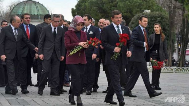 Thủ tướng Thổ Nhĩ Kỳ Ahmet Davutoglu (phải) v&agrave; phu nh&acirc;n c&ugrave;ng Bộ trưởng Nội vụ Đức Thomas de Maiziere đến đặt hoa tưởng niệm c&aacute;c nạn nh&acirc;n trong vụ đ&aacute;nh bom liều chết do khủng b&ocirc;́ IS thực hiện