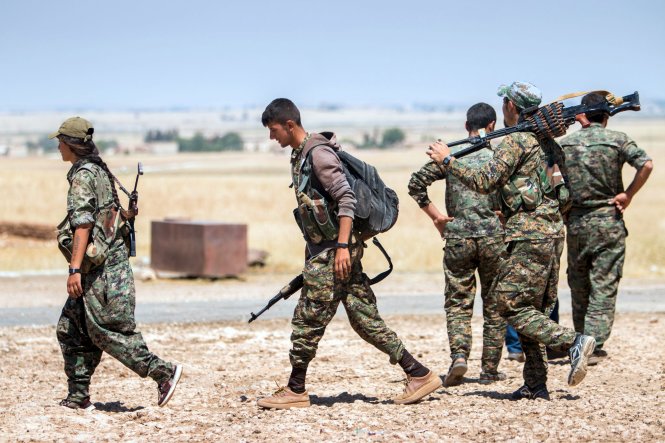 C&aacute;c binh sĩ người Kurd di chuyển b&ecirc;n ngo&agrave;i thị trấn Tal Abyad, nơi từng l&agrave; trung t&acirc;m t&agrave;i ch&iacute;nh v&agrave; hậu cần của khủng bố IS