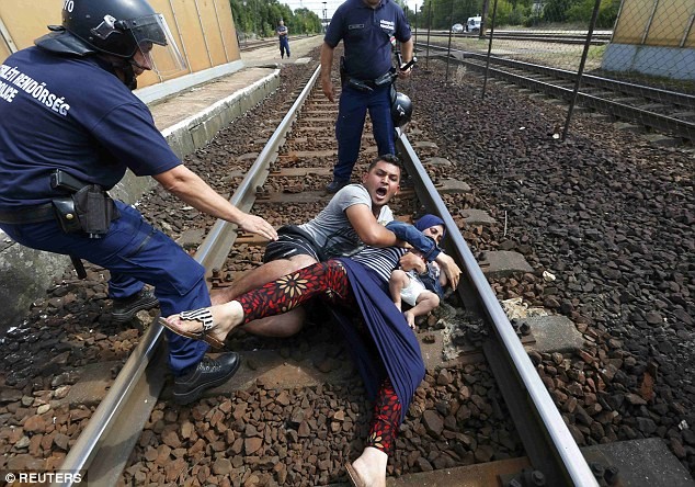 Người đàn ông trong ảnh ôm vợ và con trai, nhất quyết không nghe theo lệnh cảnh sát. Ảnh: Reuters Người đàn ông trong ảnh ôm vợ và con trai, nhất quyết không nghe theo lệnh cảnh sát. Ảnh: Reuters