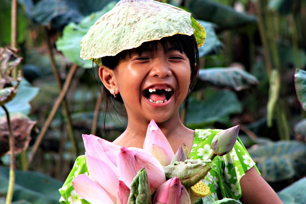 Nụ cười bình dị, trong sáng của bé gái đang ôm bó hoa sen hái được, đó cũng là nghề Đăng ký và nhận 60K 24 bao lì xì miễn phí mỗi ngày em mưu sinh. Ảnh: Zing News