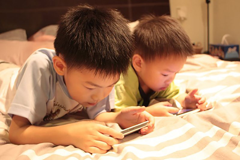 Trẻ d&ugrave;ng điện thoại di động c&oacute; nguy cơ nhiễm hội chứng TIC ((giật cơ mắt tăng cao). Ảnh minh họa 