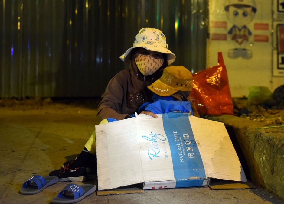 Để che chắn cho con, chị Hương (quê Bình Dương) phải lấy bìa carton phủ lên thay mền. Chị Hương vốn có nhà nhưng vì một lần con đổ bệnh nặng mà phải bán hết của cải để chữa trị, và giờ hai mẹ con sống vất vưởng ngoài đường. Ảnh: Zing News
