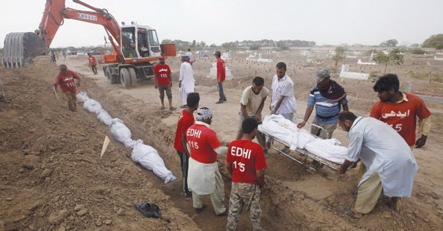 Pakistan d&ugrave;ng m&aacute;y x&uacute;c để đ&agrave;o mộ tập thể, ch&ocirc;n cất những người thiệt mạng v&igrave; đợt n&oacute;ng trong th&aacute;ng 6. Ảnh Reuters