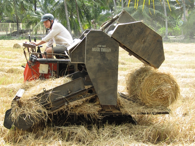 Anh Nguyễn Ngọc Thuận đang vận h&agrave;nh thử m&aacute;y cuốn rơm tự h&agrave;nh