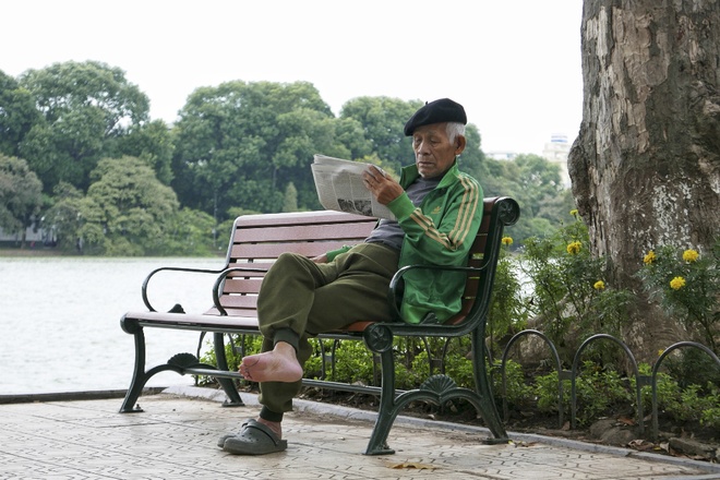 Nếu không phải di chuyển bằng xe máy, thời tiết sáng nay khá lý tưởng. Tiết trời mát mẻ kèm gió nhẹ, cụ già khoách thêm chiếc áo nỉ mỏng, ung dung ngồi bên hồ Gươm, tận hưởng buổi sáng Chủ nhật giao mùa. Ảnh VnExpress