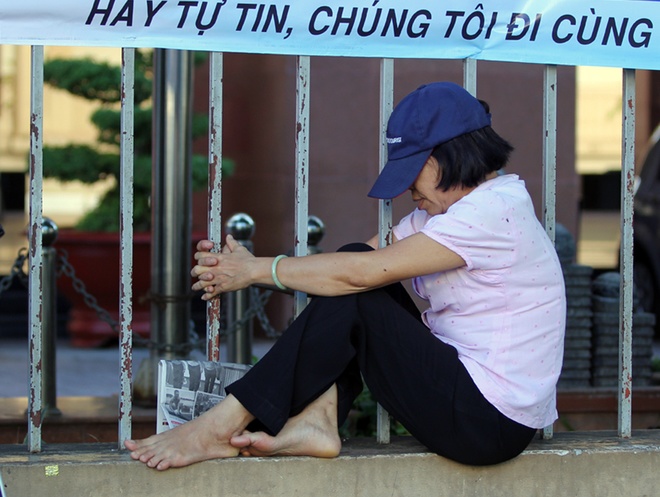 Cùng con có mặt tại điểm thi trường Đại học khoa học Xã hội và Nhân văn TPHCM từ hơn 5h sáng, người mẹ này ngồi tựa lan can, ôm cột sắt ngóng vào trong - nơi con bà đang làm bài. Phải chờ khá lâu, bà ngủ thiếp đi. Ảnh VnExpress