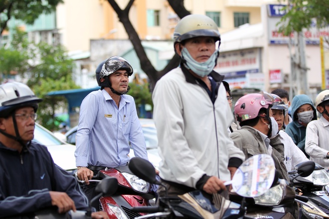 Gần hết giờ làm bài, nhiều người đứng lên ngồi xuống ngóng về phía cổng trường. Khá đông người mang xe máy xuống lòng đường đứng đợi khiến giao thông ùn ứ cục bộ. Ảnh VnExpress