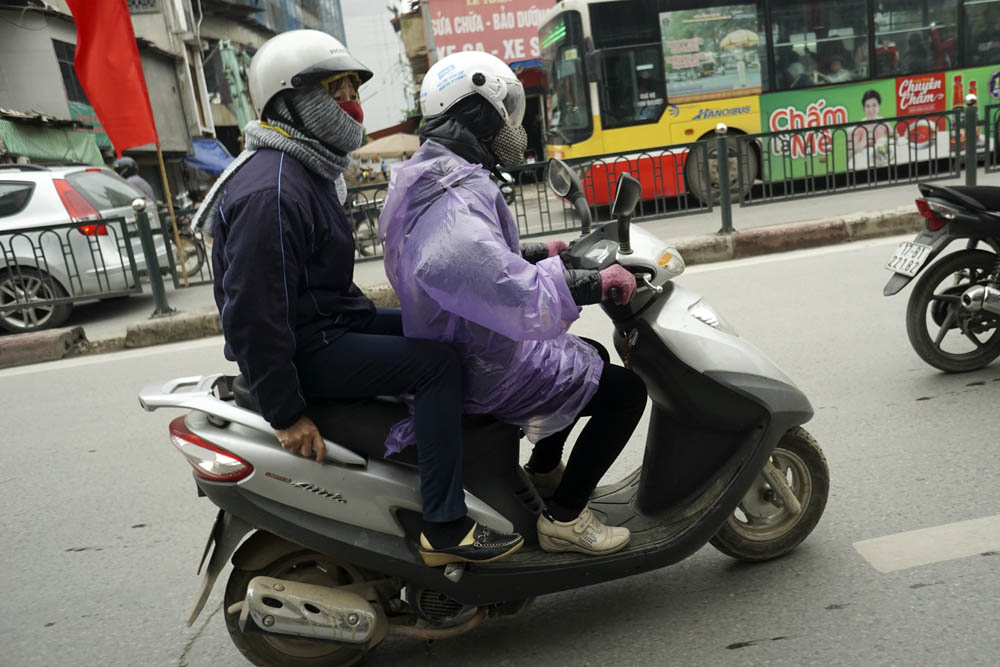 Không khí lạnh tràn về trong buổi sáng khiến nhiều người không kịp đối phó, phải mặc áo mưa chống rét. Ảnh: Dân Trí
