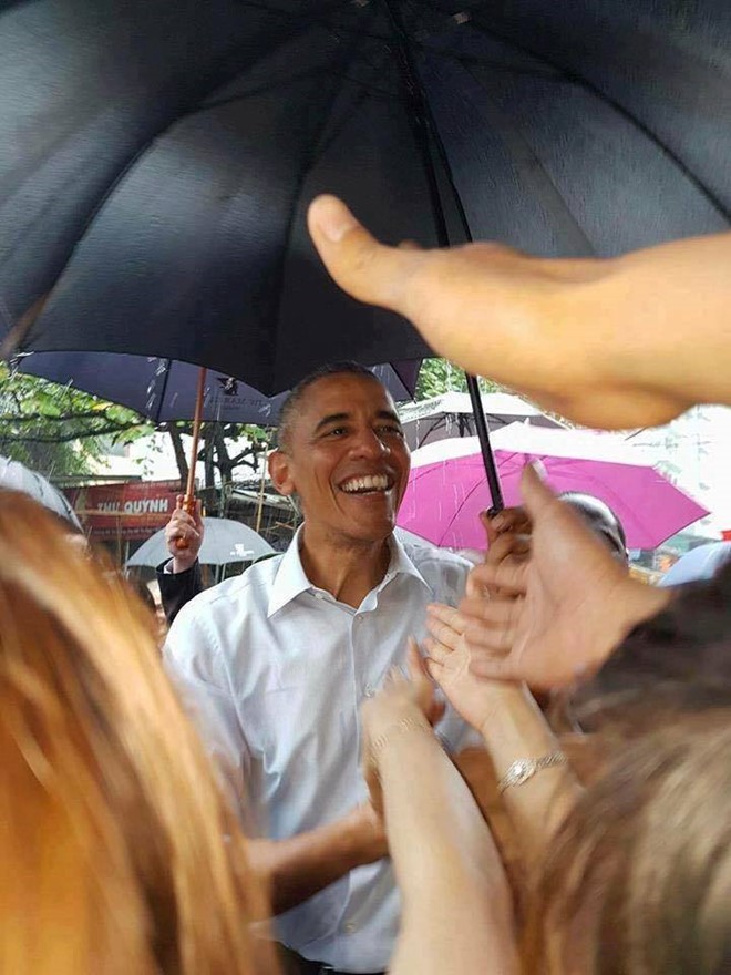 Trong cơn mưa trưa 24/5, ông Obama dừng chân ở cổng làng Mễ Trì Thượng (Nam Từ Liêm, Hà Nội), nói chuyện với một chủ quán trà đá và người dân trước khi bay vào TP HCM. Sự thân thiện của ông Obama khiến người dân địa phương thích thú. Nhiều người bày tỏ sự hạnh phúc khi được bắt tay vị tổng thống Mỹ. Ảnh: Facebook Thanh Tùng