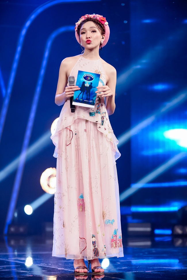 Để phù hợp với chủ đề đêm thi, nữ  MC của chương trình- Cao Thanh Thảo My diện bộ đầm yếm cách điệu điệu màu hồng nhạt, thiết kế vừa giúp cô khoe vẻ thướt tha, mềm mại, vừa khoe vai trần gợi cảm. Chiếc mấn đội đầu giúp tổng thể bộ trang phục thêm ấn tượng.