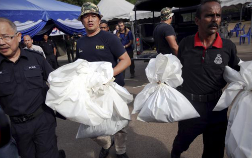 Nh&acirc;n vi&ecirc;n ph&aacute;p y Malaysia mang những chiếc bao đựng thi thể sau khi cảnh s&aacute;t nước n&agrave;y t&igrave;m thấy h&agrave;ng trăm ng&ocirc;i mộ tập thể 