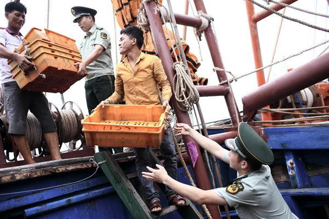 Qu&acirc;n đội Trung Quốc hỗ trợ ngư d&acirc;n chuẩn bị cho việc đ&aacute;nh bắt (tr&aacute;i ph&eacute;p) tr&ecirc;n Biển Đ&ocirc;ng