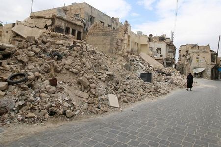Một phụ nữ đi ngang những t&ograve;a nh&agrave; đổ n&aacute;t ở Aleppo, theo tình hình chi&ecirc;́n sự Syria mới nh&acirc;́t