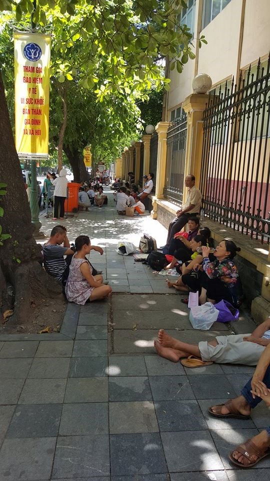Những ngày này, Hà Nội về trưa nắng nóng tới gần 40 độ C. Trong các bệnh viện đông đúc, cảm giác nóng bức càng tăng lên. Nhiều bệnh nhân và người nhà dắt nhau ra ngoài khuôn viên bệnh viện tìm kiếm những bóng mát để tranh thủ nghỉ ngơi. Trong ảnh: bệnh nhân và người nhà bệnh nhân vạ vật tránh cái nắng oi bức 12h trưa ngày 29/6/2015 tại bệnh viện K Hà Nội.