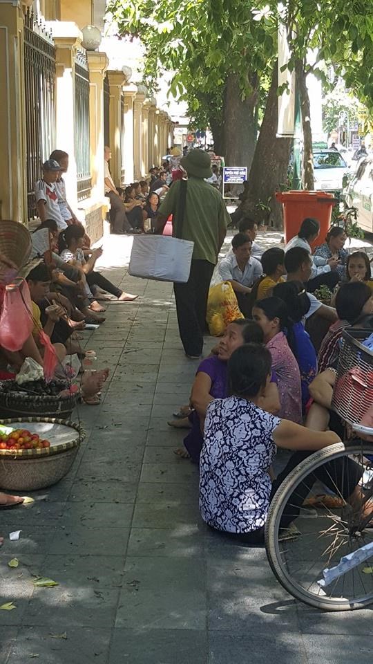 Mọi người tranh thủ nghỉ trưa tránh nắng dưới những bóng cây cổ thụ 2 bên vỉa hè. Mọi bóng mát đều được tranh thủ.